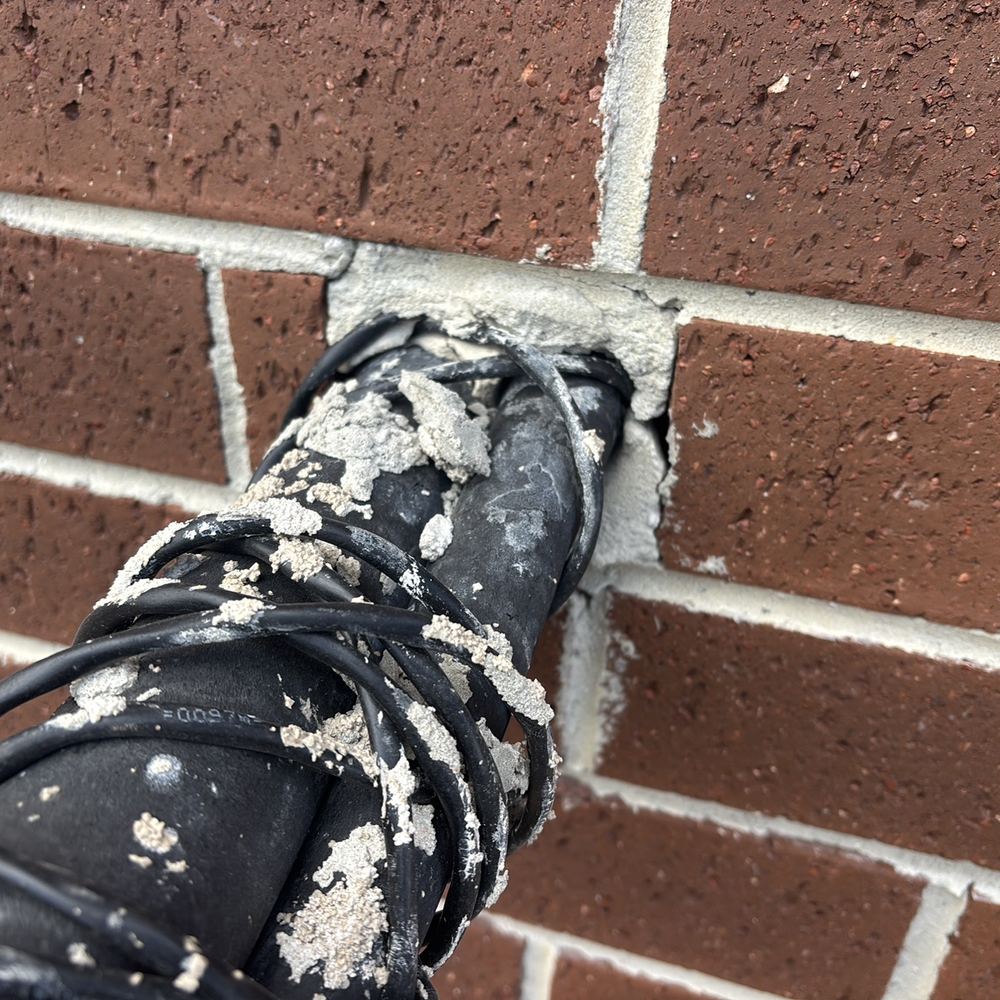 Pipe through the external wall left without grout or caulking around it, found during a pre-handover inspection in Kalkallo