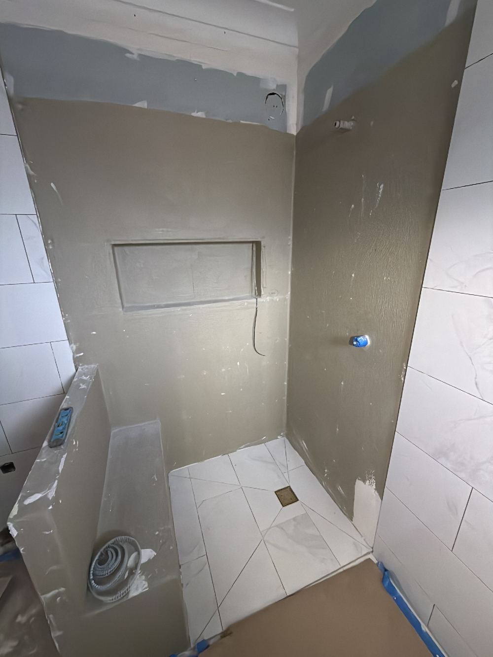 Shower wall membrane punctured in many places by mechanical fixings, found during a waterproofing inspection in Chelsea